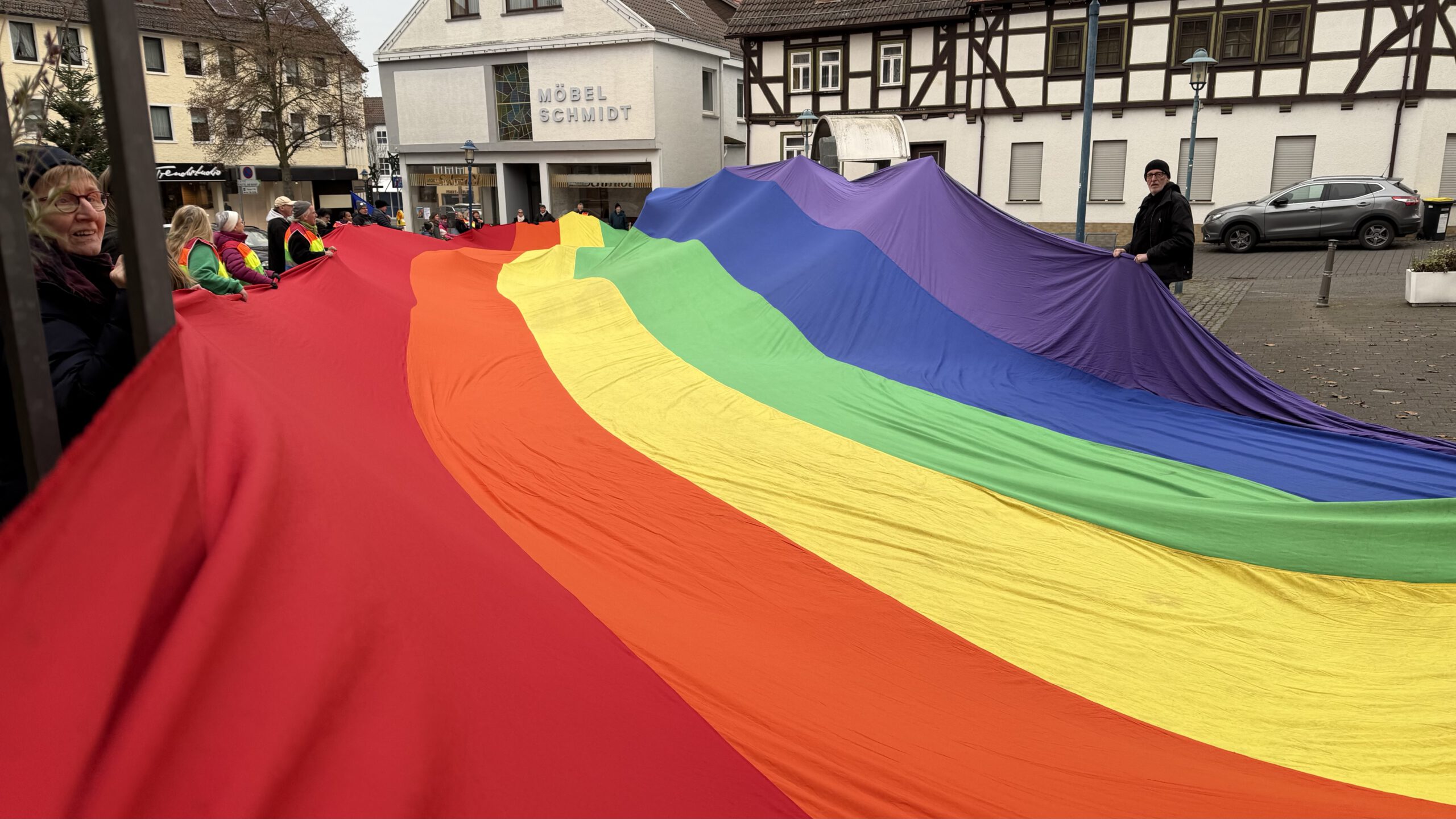 Menschen mit einer großen Regenbogenfahne auf dem Hungener Marktplatz